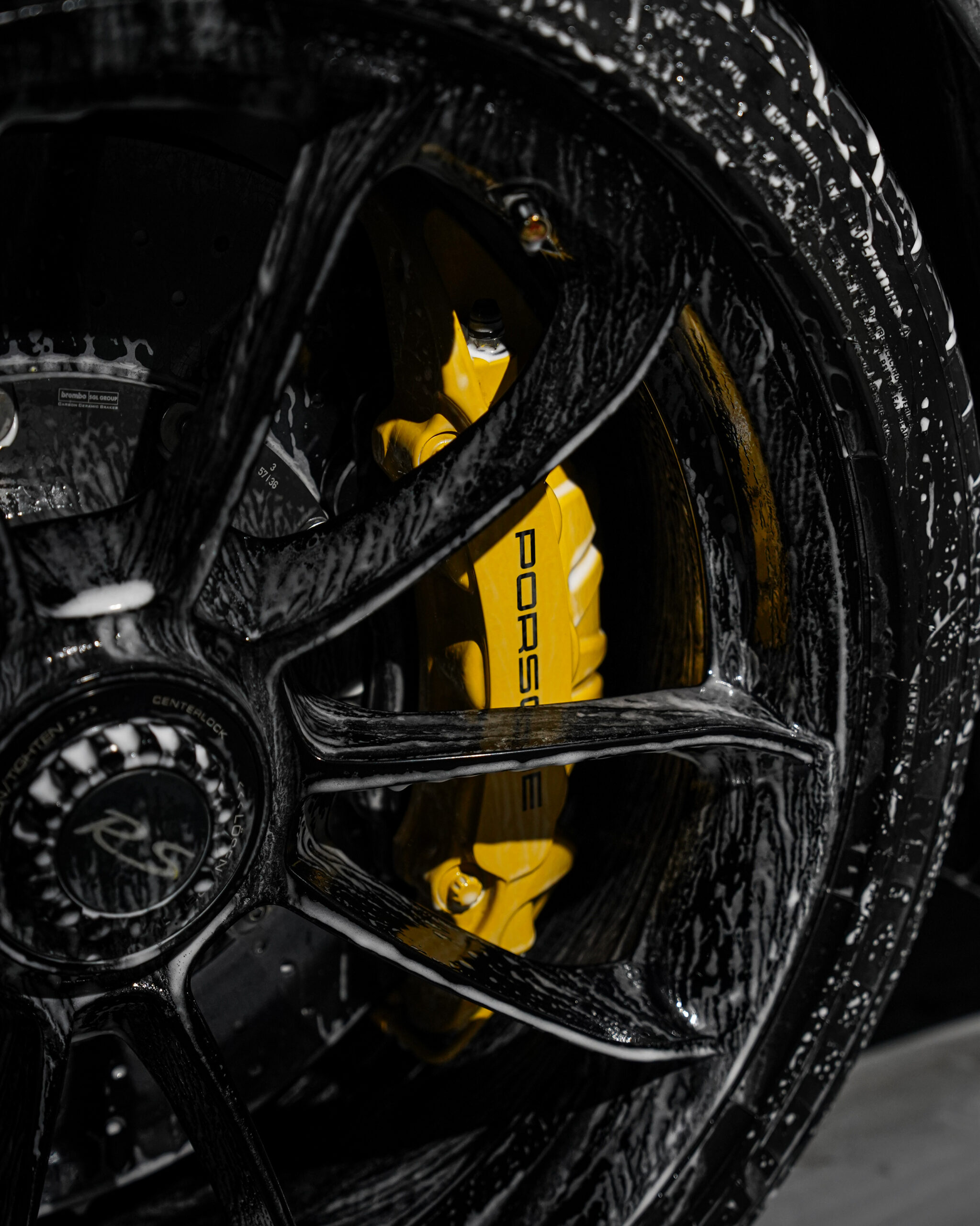 Snow foam across the wheel and paint of a Porsche